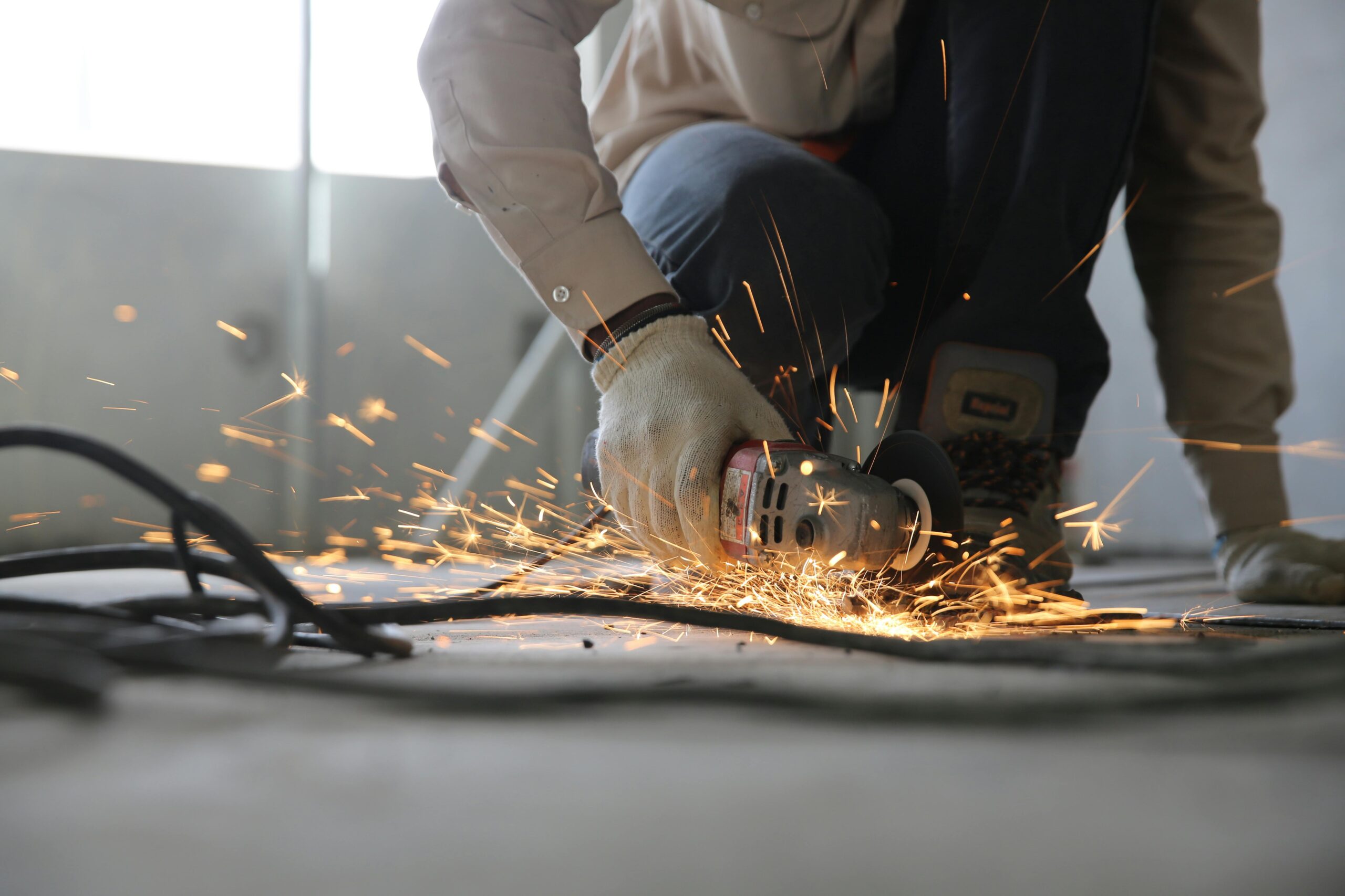 Servicios A skilled industrial worker uses a grinder creating a burst of sparks indoors.
